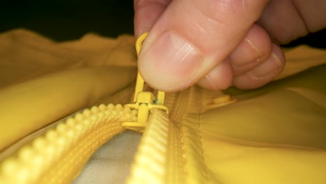 Macro-shot-of-unzipping-the-zipper-of-a-yellow-raincoat