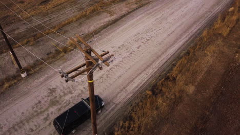 SUV-parked-on-a-dusty-road-under-the-power-line,-Moreno-Valley-Upland-Game-Hunting-Area,-aerial-overhead-shot