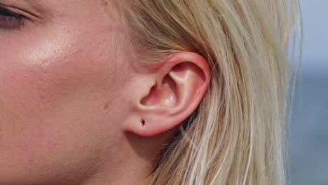 Close-up-shot-of-wound-hole-in-ear-lobe-of-blonde-woman,macro-view