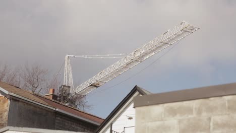 Canada---White-Tower-Crane-Boom-Over-The-House-Roof-On-A-Sunny-Day---Low-Angle-Shot