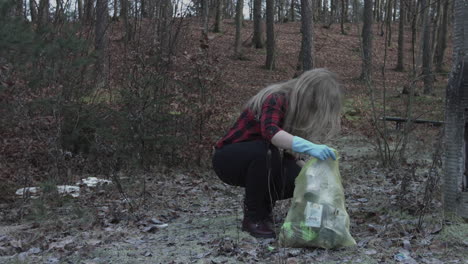Young-woman-gloves-is-picking-up-trash-to-the-bag-from-ground-for-cleaning-the-earth