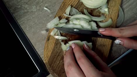 Slicing--dicing-onion-on-a-small-wooden-cutting-board,-closeup