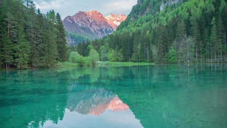Beautiful-Jezersko-lake-with-sunny-Alps-mountains-in-background-surrounded-with-trees