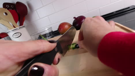 POV-shot-of-woman-chopping-spicy-jalapenos-on-cutting-board