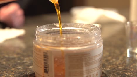 Golden-beeswax-and-CBD-infused-coconut-oil-be-poured-into-container