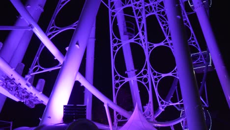People-Riding-A-Giant-Ferris-Wheel-Glowing-With-Amazing-Purple-Lights---Medium-Shot
