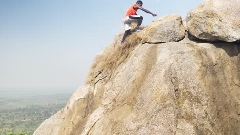 A-slow-motion-shot-of-a-young-African-man-climbing-a-dangerous-summit-on-a-granite-mountain-Africa