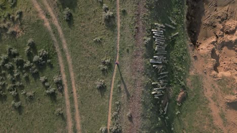 Vertical-aerial-tracks-hiker-walking-along-old,-disused-railway-track