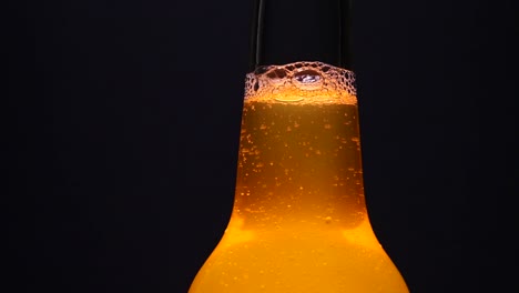 Backlit-long-neck-cold,-fresh-bottle-of-amber-beer-with-bubbles-rising