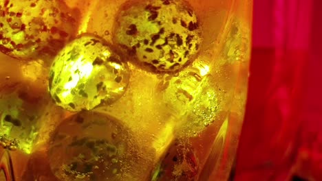plastic-colored-ice-round-cubes-and-orange-effervescent-vitamin-c-flu-tablet-dissolving-in-a-glass-of-water,-sparkling-and-fizzing-bubbles