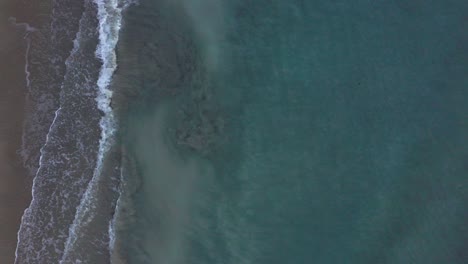 drone-view-of-tropical-beach,a-bird's-eye-view-of-ocean-waves-crashing-against-an-empty-beach-from-above