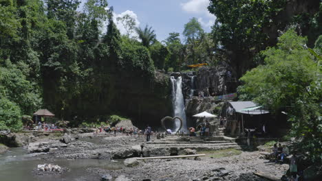 Fliegen-Sie-Durch-Die-Schlucht-Mit-Dem-Tegenungan-Wasserfall-Und-Zahlreichen-Touristen,-Die-Sich-An-Seinem-Grund-Versammeln