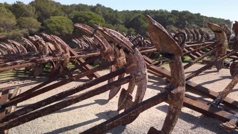Pull-Back-Shot-of-rusty-anchors-stored-in-rows-at-port-of-Barbate,-Cadiz,-Spain