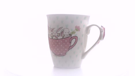 Tasse-Tee-Mit-Ilustracion-Kleine-Kaninchen-Auf-Weißem-Hintergrund-Im-Fotostudio