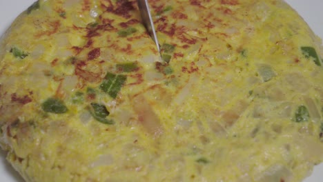 Knife-cuts-into-Tortilla-Espanola-or-Spanish-Omelette-and-takes-piece,-Closeup