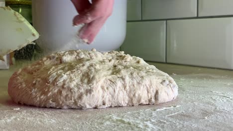 Throwing-and-sprinkling-flour-over-dough-on-table-in-slowmotion