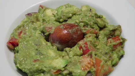 Tilt-Down,-Bowl-of-Fresh-Guacamole-with-Avocado-Pit,-Closeup