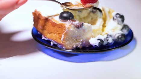 Mascarpone-cake-with-blueberries-and-raspberries,-a-woman-with-a-spoon-takes-a-berry