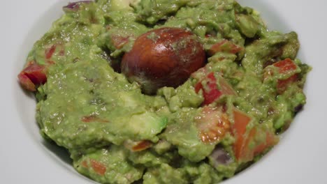 Tilt-Up,-Bowl-of-Fresh-Guacamole-with-Avocado-Pit,-Closeup