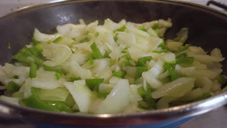 Steam-rising-off-onion-and-green-pepper-in-frying-pan,-Slowmo-Closeup