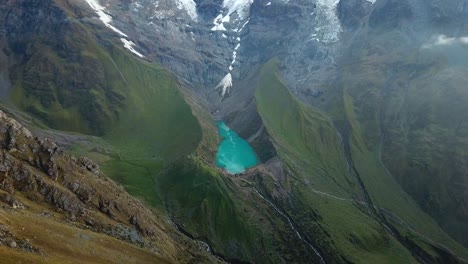 Aerial,-drone-shot-towards-emerald-color,-lake-Humantay,-Andes-mountains,-overcast-day,-in-Peru,-South-America
