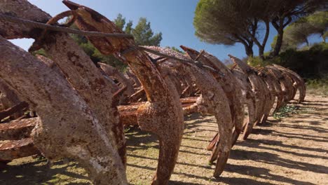 Walking-Past-Row-of-Rusty-Anchors-Covered-in-Barnacles-Stored-on-Land