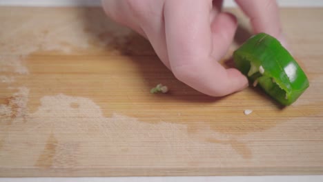 Hands-scoops-up-green-pepper-slices-from-wooden-cutting-board,-Closeup