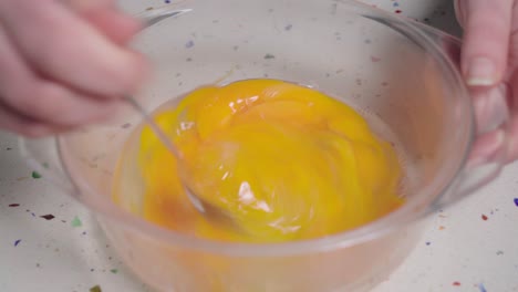 Whisking-raw-eggs-fast-with-fork-in-glass-bowl,-Closeup-on-Hands