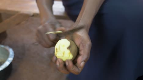 Nahaufnahme-Von-Oben-Nach-Unten-Von-Der-Hand-Einer-Afrikanischen-Frau,-Die-Kartoffeln-Mit-Einem-Messer-Schält