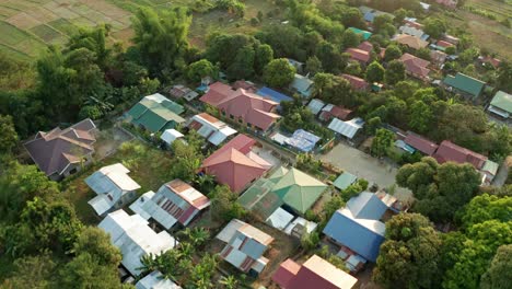 Luftaufnahme-Eines-Kleinen-Modernen-Dorfes-In-Einem-Wald-Neben-Einer-Farm-Auf-Den-Philippinen-Bei-Sonnenuntergang-In-4k