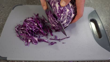 Cropped-view-of-a-man-slicing-red-cabbage-in-a-kitchen-top-view