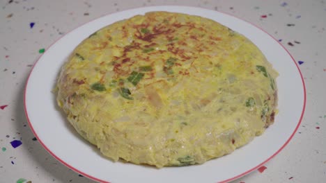 Hands-place-finished-Tortilla-Espanola-or-Spanish-Omelette-in-frame,-Closeup