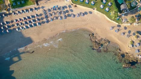 Aerial-Top-Down-View-Of-Tropical-Beach-With-Umbrellas-And-Calm-Crashing-Waves-At-Zakynthos
