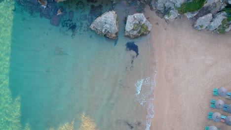 Aerial-Dolly-Over-Turquoise-Waters-On-Beach-Next-To-Rock-Cliffs