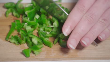 Hands-dicing-green-pepper-by-rocking-knife-back-and-forth,-Closeup