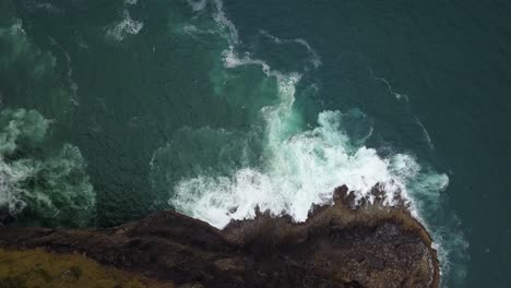 Overhead-aerial-view-of-waves-splashing-below-cliffs-on-the-Oregon-coast