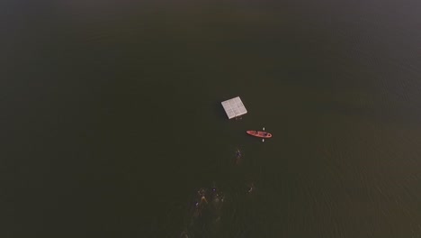 Aerial-view-of-kids-swimming-to-a-lake's-platform-in-a-summer-camp