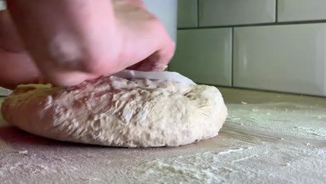 Female-hands-processing-sticky-dough-for-bread-with-a-plastic-cleaning-card-at-home