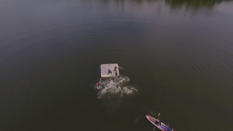 Aerial-view-of-kids-having-fun-jumping-from-a-platform-to-a-summer-camp's-lake