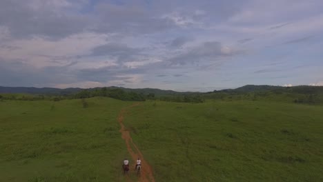 Zwei-Reiter-Galoppieren-Durch-Einen-Roten-Feldweg-In-Einer-Venezolanischen-Ebene,-Zeitlupe
