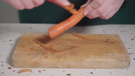 Caucasian-woman-peeling-carrot-over-wooden-cutting-board,-Closeup