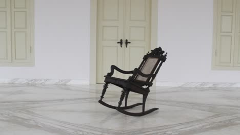 a-single-wooden-chair-rocking-in-front-of-the-colonial-house
