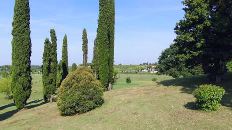 Aerial-drone-footage-flying-through-large-trees-and-tracking-round-a-garden,-Italy