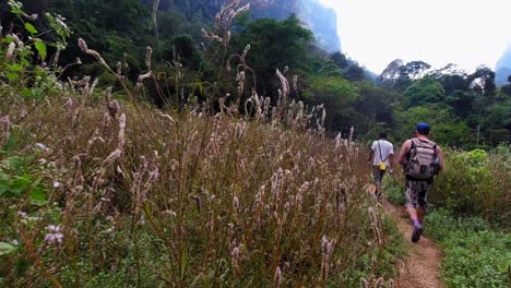 Group-of-tourists-walking-through-a-long-narrow-trail-heading-to-the-lush-green-nature's-park-in-Khao-Sok-in-Thailand---Long-shot