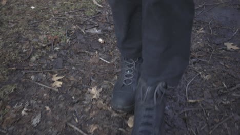 A-Person-Wearing-Black-Shoes-Walking-On-The-Messy-And-Muddy-Walkway