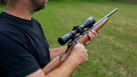 Middle-aged-white-Caucasian-man-cocks-cabin-of-hunting-snipers-rifle-made-of-wood-and-metal-and-takes-aim-down-the-scope-before-firing-at-a-shooting-range
