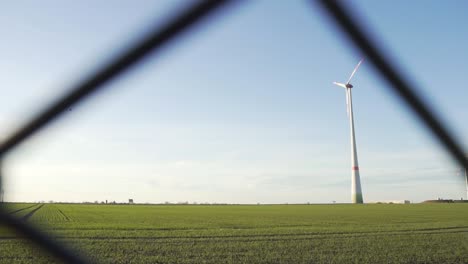 Einzelne-Windkraftanlage-Mit-Rotierenden-Rotorblättern-Auf-Der-Grünen-Wiese-In-Zeitlupe