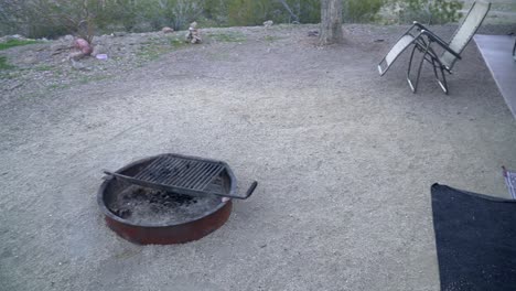 Pan-of-campsite-with-fire-ring,rug-and-lawn-chair