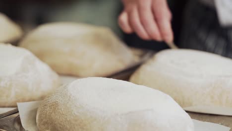 Nahaufnahme,-Der-Bäcker-Schneidet-Durch-Und-Verziert-Das-Rohe-Hausgemachte-Brot,-Bevor-Er-Im-Ofen-Backt