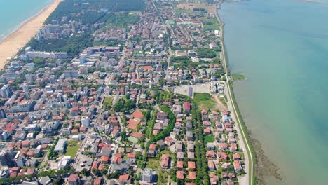 Aerial-tilt-revealing-Lignano-Sabbiadoro-town-located-on-a-narrow-strip-of-land-surrounded-by-water
